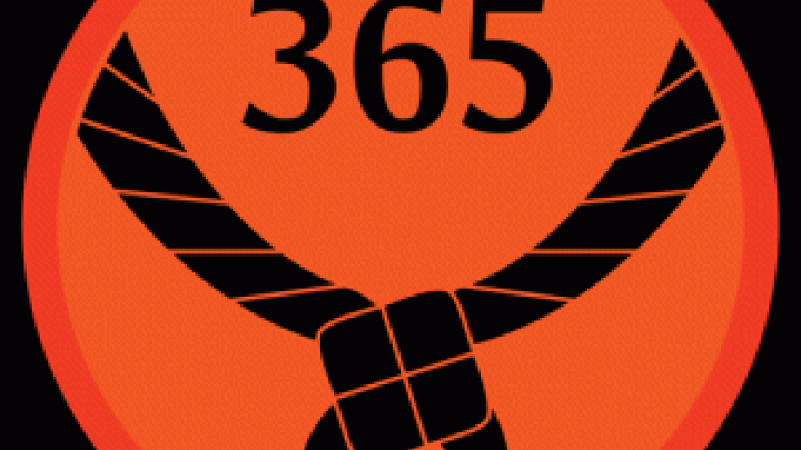 Rundt orange mærke med et sort tørklæde og 365 stående med sorte bogstaver