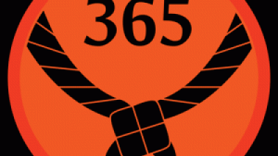 Rundt orange mærke med et sort tørklæde og 365 stående med sorte bogstaver